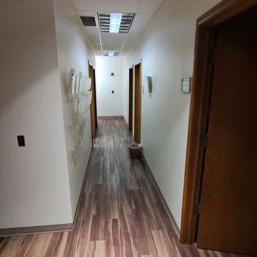 Clean office hallway, with an emptied trash can sitting outside of one of the offices.