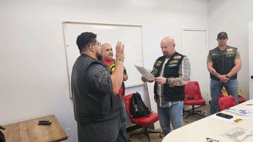 Four men in a room, with one man taking an oath.