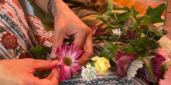 Hands arranging colorful flowers on fabric.