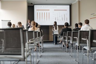 Presentation and discussion in a meeting room with content projected on a screen.