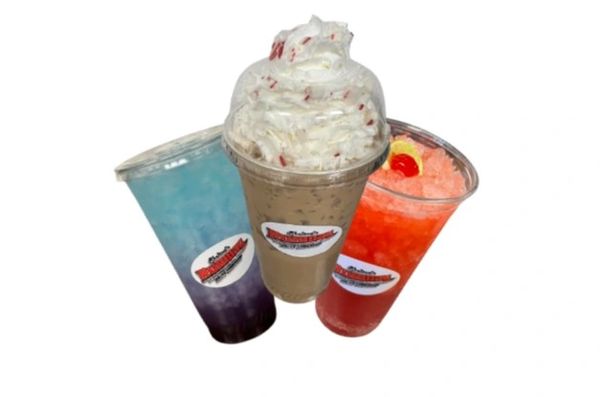 Three colorful drinks with whipped cream and cherry toppings.