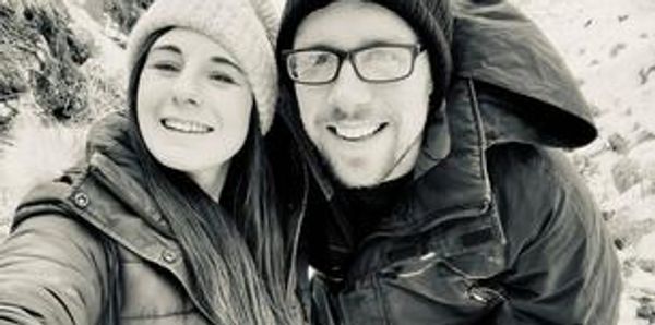 A happy couple in winter clothing taking a selfie outdoors.