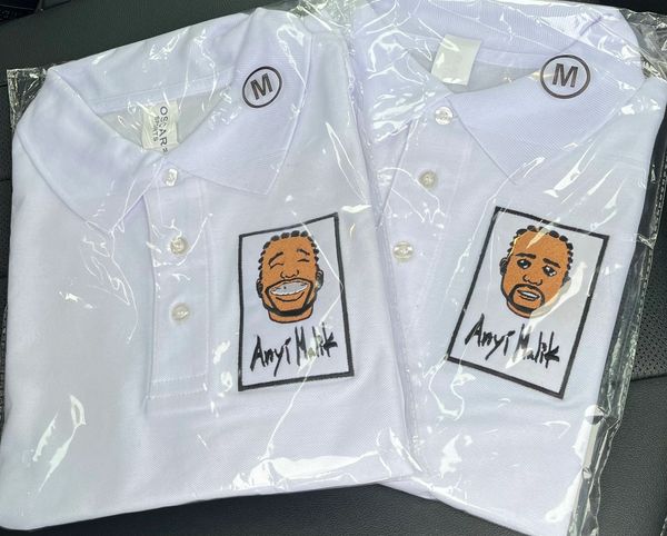 Two white polo shirts with cartoon faces and 'Angi Malik' text, size medium, in plastic packaging.