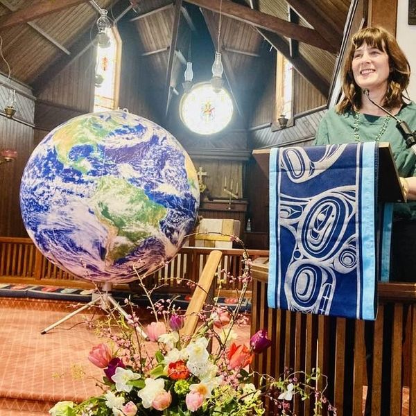 Woman speaking in a church with a globe and flower arrangement.