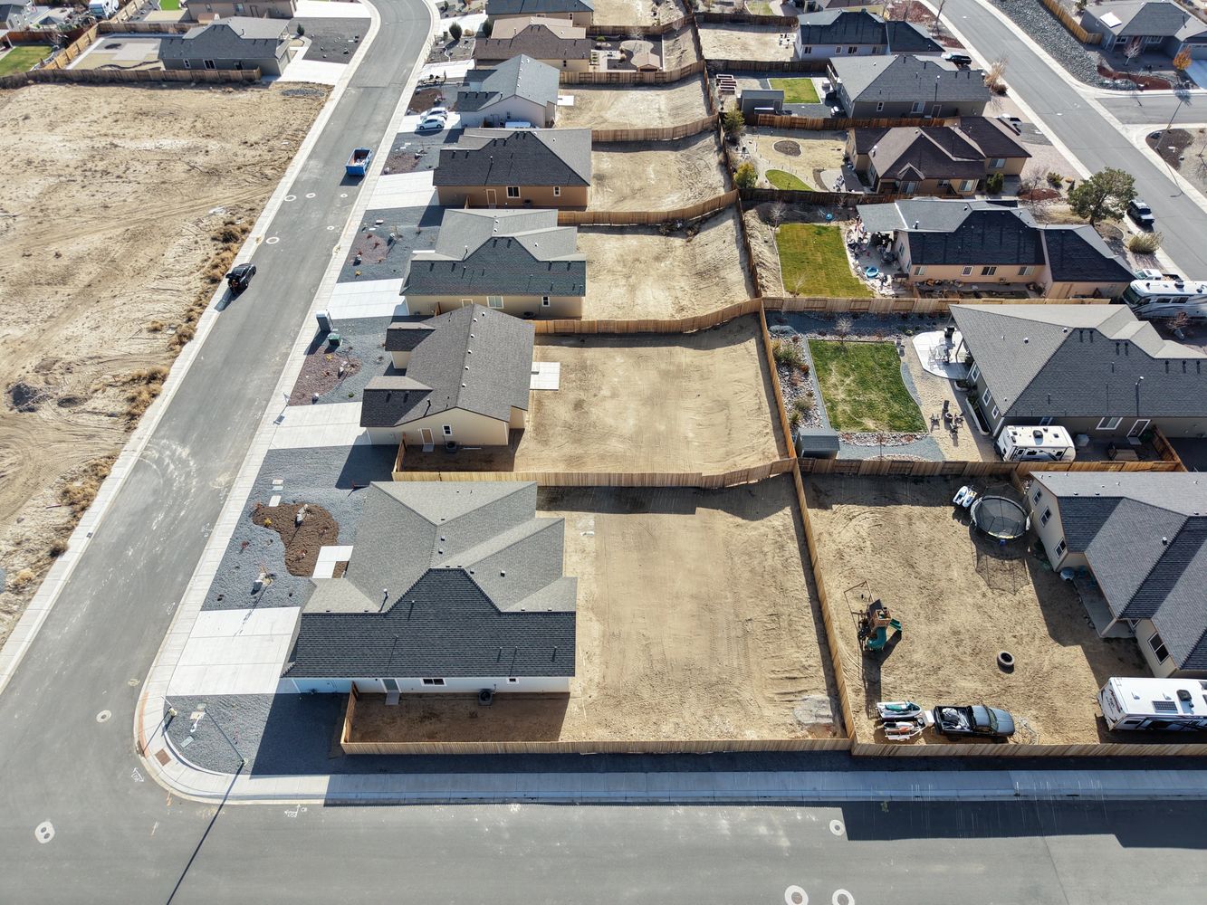 Aerial view of suburban homes with empty fenced lots and paved streets.