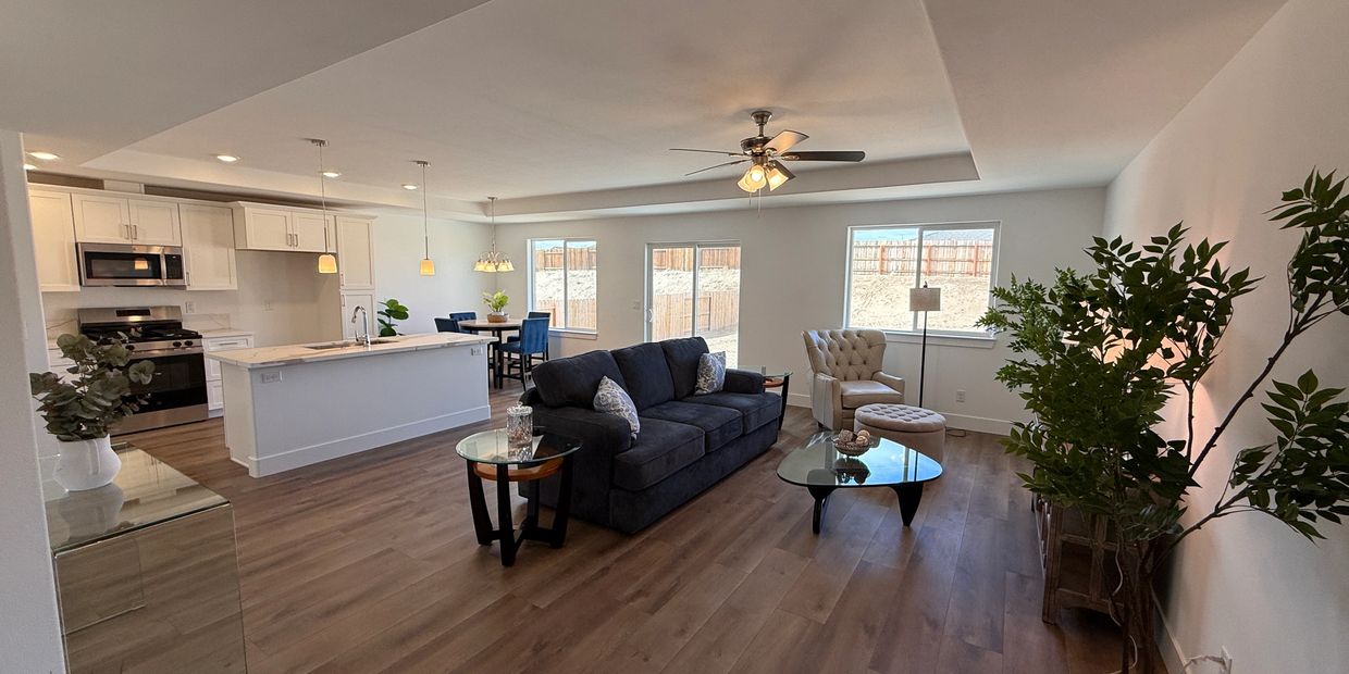 Modern open-concept living room and kitchen with wood flooring and large windows.