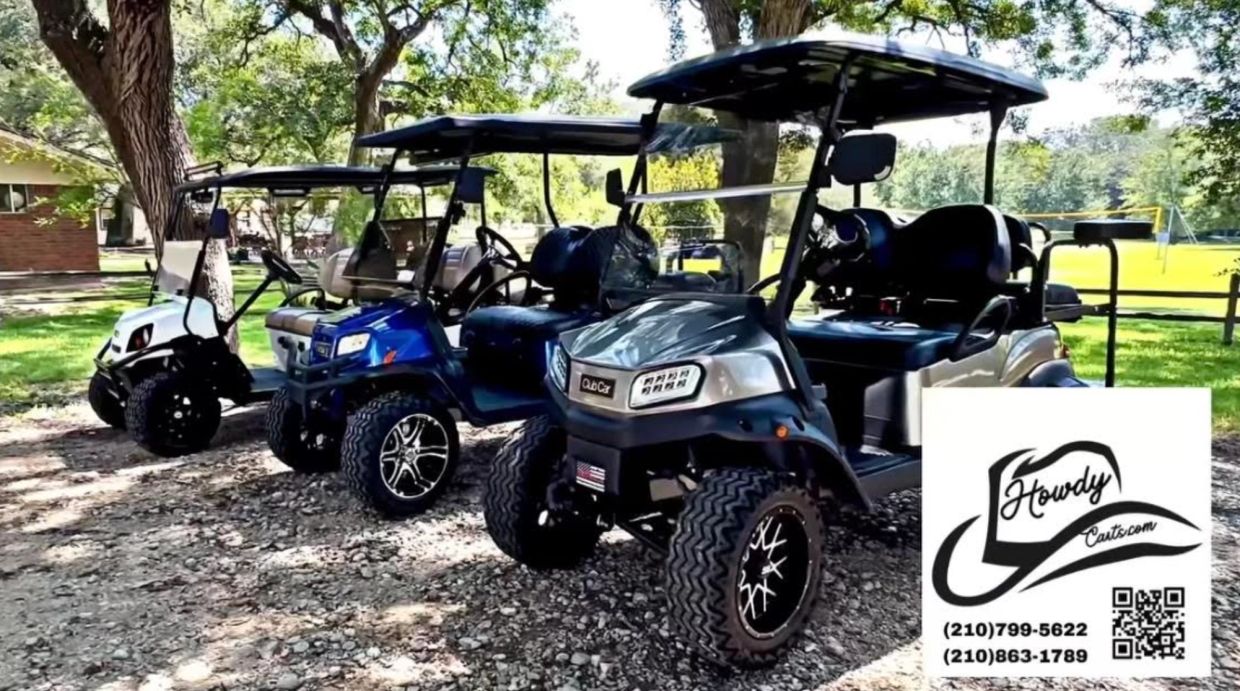 Three golf carts parked outdoors in a row under trees.
