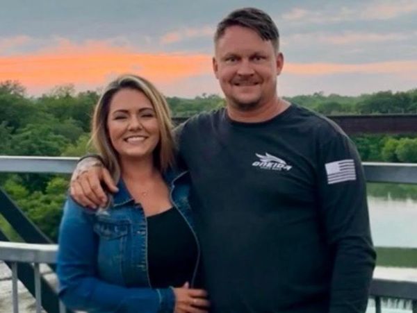 Smiling couple posing on a bridge during sunset.