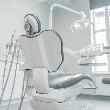 Modern dental chair and equipment in a bright clinic room.