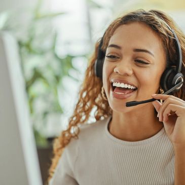 Smiling woman with headset working on a computer.