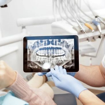 Dentist showing a dental X-ray on a tablet to a patient.