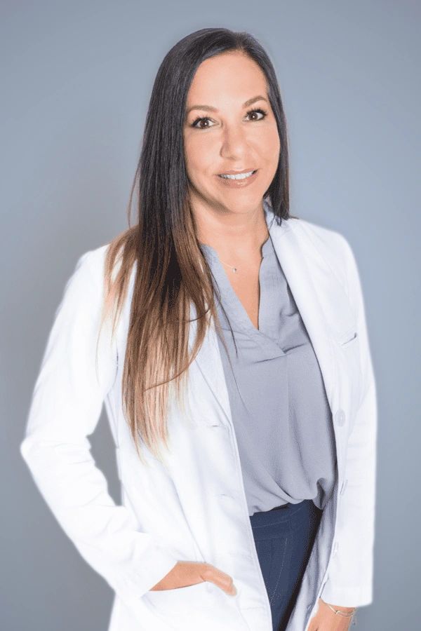 Professional woman in a white coat smiling gently.