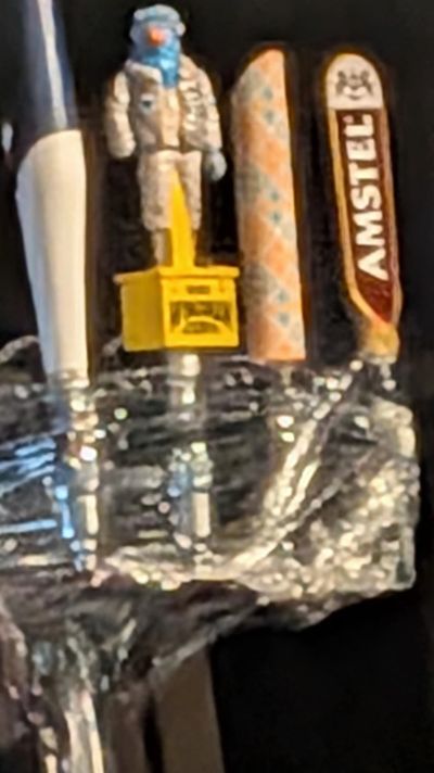 Close-up of beer tap handles including an astronaut figure and Amstel.