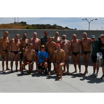 Group of men in swimwear posing outdoors on a sunny day.