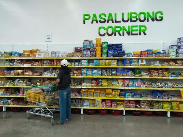 A person shopping at Pasalubong Corner stocked with various snacks and treats.