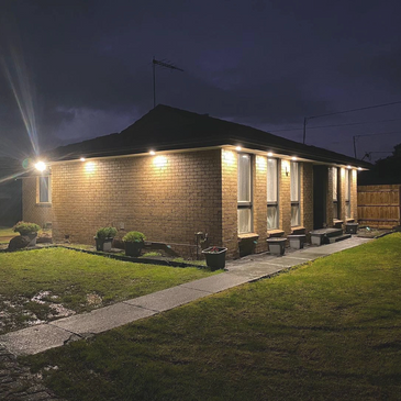 External flood lights around single story home at night lighting up the home