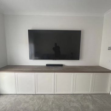 Tv wall mounted in living room above cabinetry 