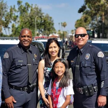 Police officers and family posing outdoors.
