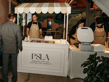 PSLA personalization booth with staff assisting a visitor indoors.