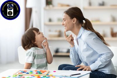 A speech therapist teaches a young boy to articulate sounds using visual cues.