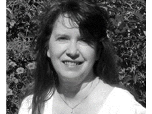 Black and white portrait of a smiling woman outdoors.