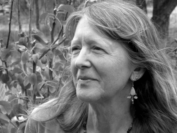 Black and white portrait of a mature woman with long hair outdoors.