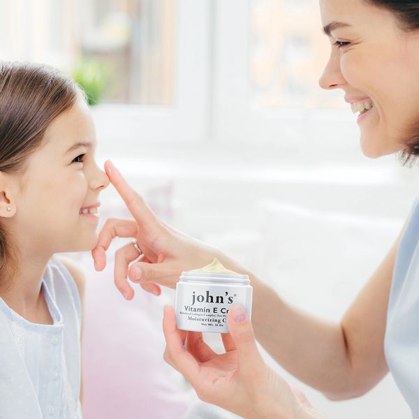 Mom smiling and rubbing in john's creme on her daughter's nose