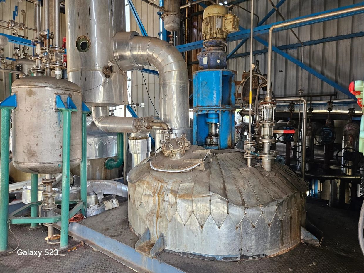 Industrial machinery with large metallic tanks and pipes inside a factory.