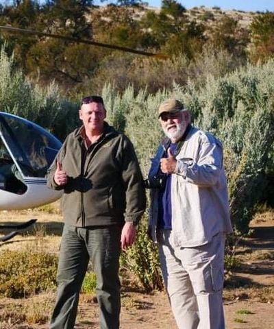 Two people standing with a helicopter behind