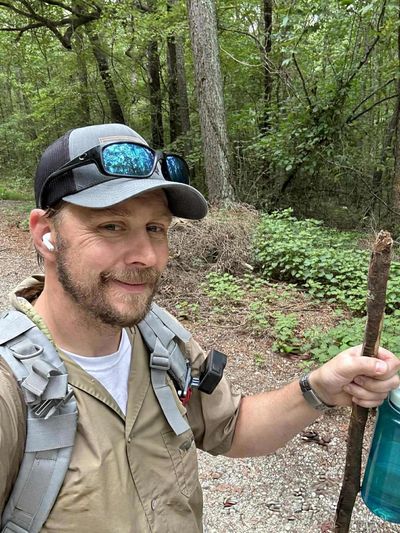 Man hiking in the forest with a walking stick.