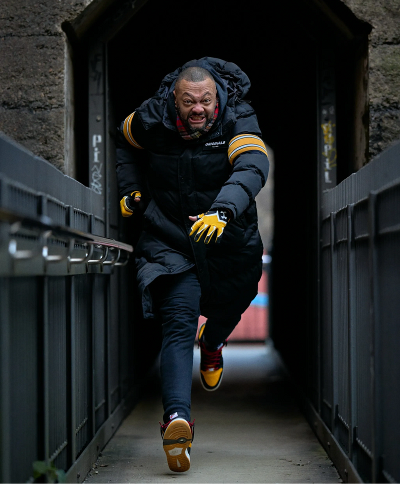 Gene Stovall in a black coat running aggressively towards the camera.