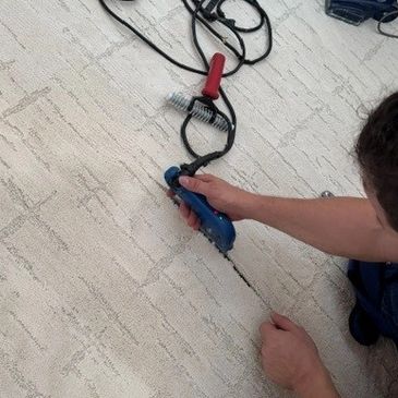 Person using a tool to cut a carpet along a marked line.