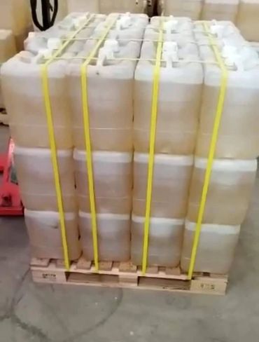 Stacked white plastic containers secured on a wooden pallet with yellow straps.