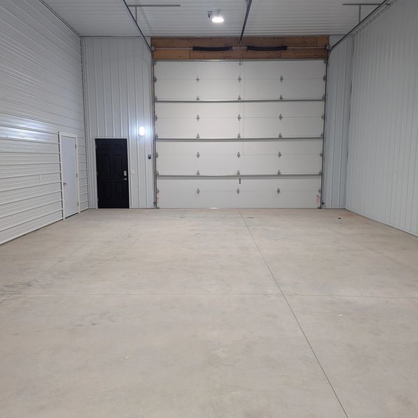 Empty, clean garage with white walls and a large overhead door.