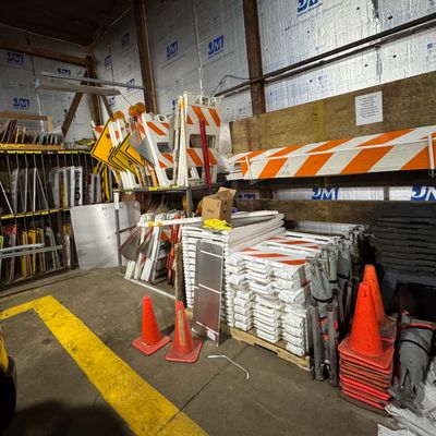 Storage area with traffic cones, barricades, and road signs organized inside a warehouse.