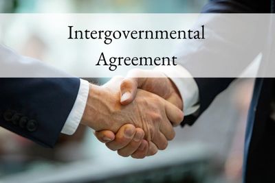 Two businesspeople shaking hands under the text 'Intergovernmental Agreement'.