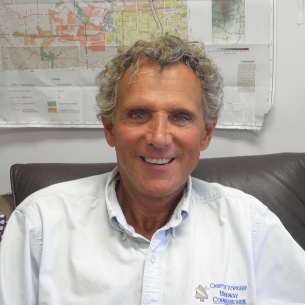 Smiling man in a white shirt sitting in front of a map.
