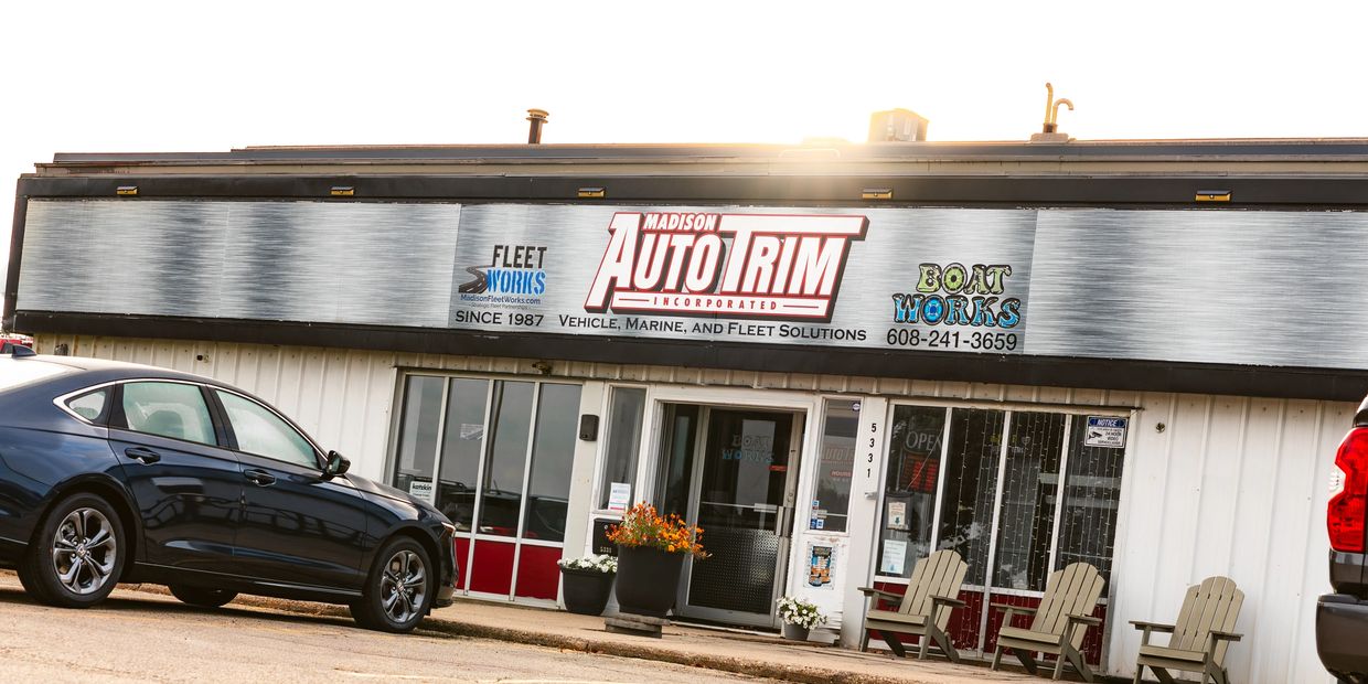 Exterior of Madison Auto Trim with parked cars and chairs outside.