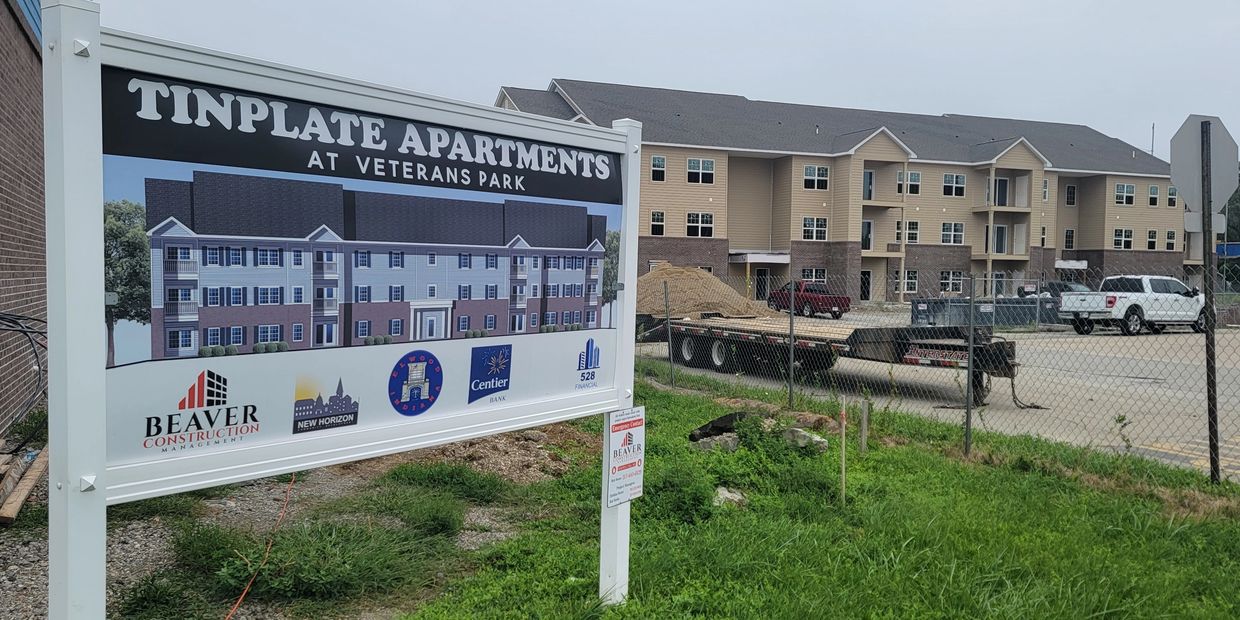 Sign for Tinplate Apartments at Veterans Park with construction in progress.