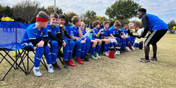 Youth soccer team listening to coach on sidelines during a game.
