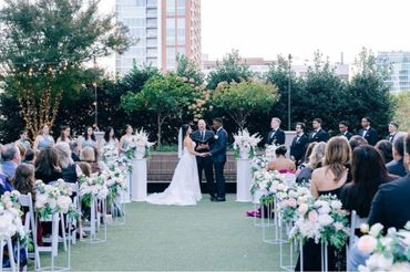 Outdoor wedding ceremony with bride, groom, and guests seated.