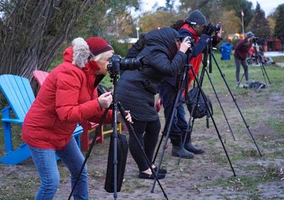 Photographers in warm clothing using tripods outdoors.