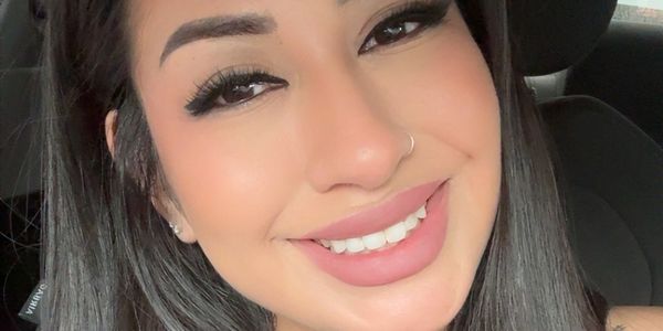 Close-up of a smiling woman with long dark hair and makeup.