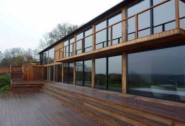 External view of remodelled house with timber cladding and extensive glazing.