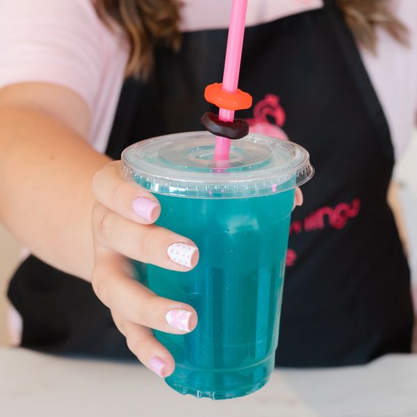 a pink flamingo barista hands a beverage to a customer.