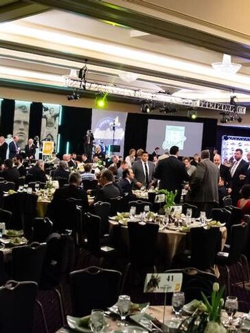 Formal banquet with people socializing and dining at round tables.