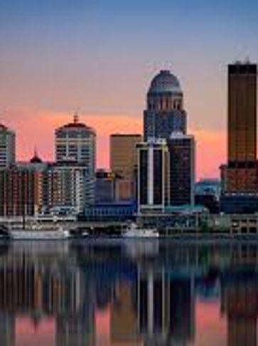 City skyline reflecting on calm water at sunset.
