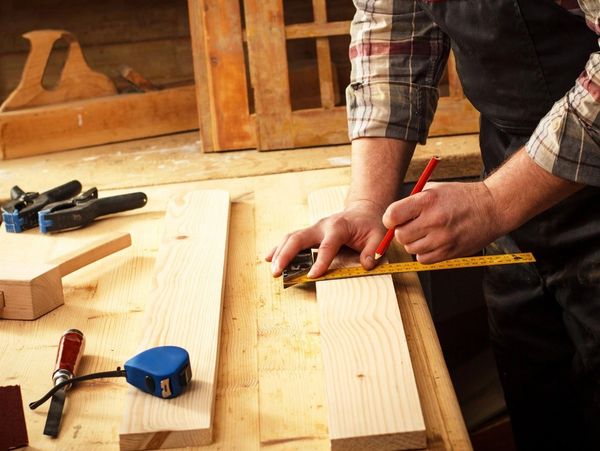 Carpenter Marking a Measurement on a Wooden Plank