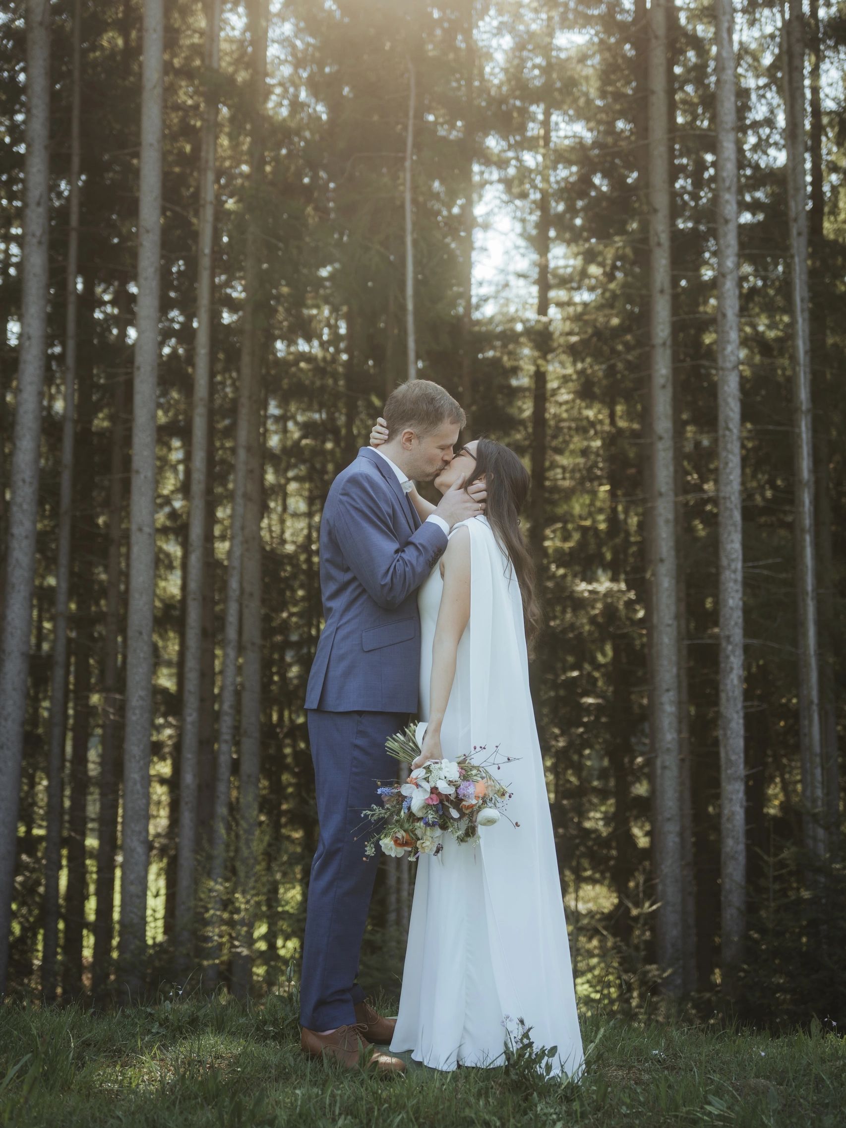 Ein Paar küsst sich in einem Wald an ihrem Hochzeitstag.