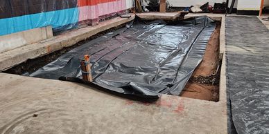 A construction site with plastic sheeting covering the ground.